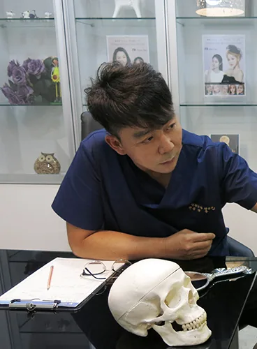 두개골 모형을 책상에 두고 상담하는 박용남 대표원장